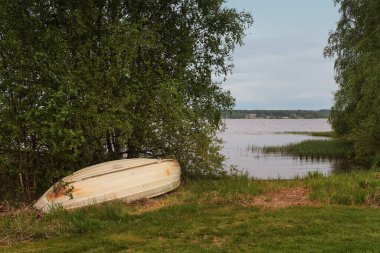 Finlandiya 'nın kırsal kesimindeki bir gölde eski bir plastik kayık baş aşağı çevrilmiş..