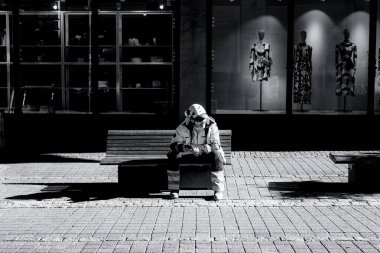 A street worker is sitting on a bench and looking at his phone. He keeps an eye to the work site, too. Maybe he's a supervisor.