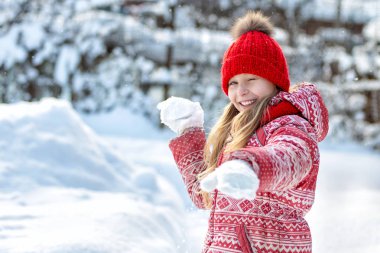 Kış mutlu bir çocuk portresi. Neşeli kız açık havada. Snowball oyunu