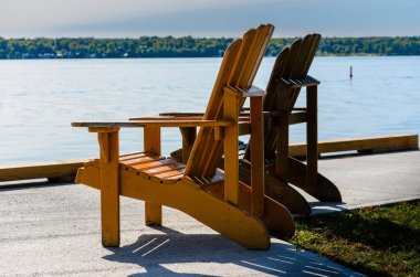 İki Adirondack sandalyesi St. Lawrence Nehri 'nin kenarında solda.