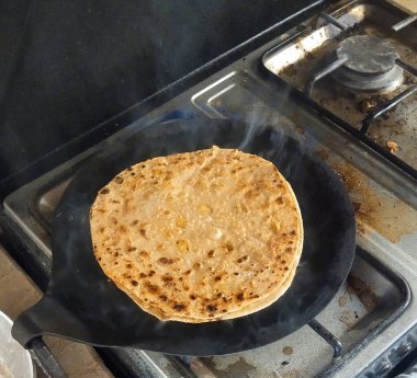 Hamuru, ızgaranın üzerindeki altın, pullu katmanlara dönüştür. Evde lezzetli, çok yönlü Pakistan ekmeği pişirme sanatı.