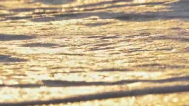 Sahil dalgası günbatımında makro su sıçratıyor.