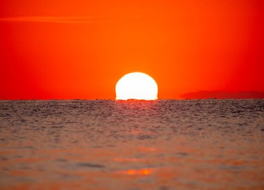 Büyük güneş denizin üzerinde batıyor. Gün doğuyor, kızıl gökyüzü.