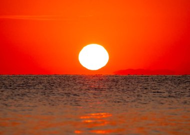 Büyük güneş denizin üzerinde batıyor. Gün doğuyor, kızıl gökyüzü.