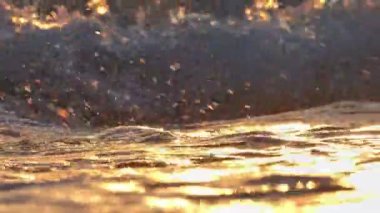 Sahil dalgası günbatımında makro su sıçratıyor.