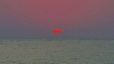 Büyük güneş denizin üzerinde, kırmızı gökyüzü yavaş çekim 4k