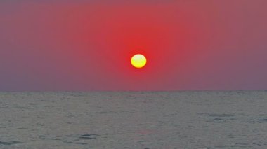 Büyük güneş denizin üzerinde, kırmızı gökyüzü yavaş çekim 4k