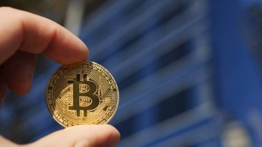 Bitcoin altın sikke ve arka planda Bina iş tutan el