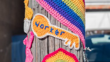 Tığ işi anahtar mesajı, arka plandaki bir yerleşim bölgesindeki telgraf direğine yerleştirilmiş anahtar şeklinde..