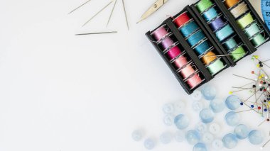 Dikiş aksesuarlarının bir tarafı tıkalı olmayan çeşitli iplikler, düğmeler, iğneler, makaslar.