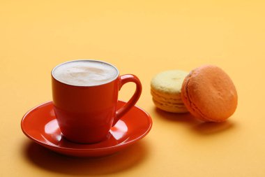 turuncu fincan kahve macaroons üzerinde sarı bir arka plan ile 