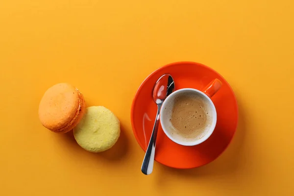 Taza de café naranja con macarrones sobre un fondo amarillo . Fotos De Stock