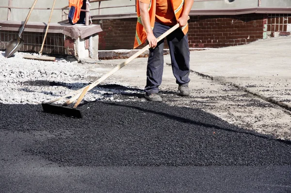 Straßenarbeiter Ebnen Den Heißen Asphalt Von Hand Stockbild