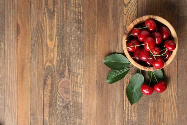 Cerezas maduras en un tazón de madera sobre una mesa de madera — Foto de Stock