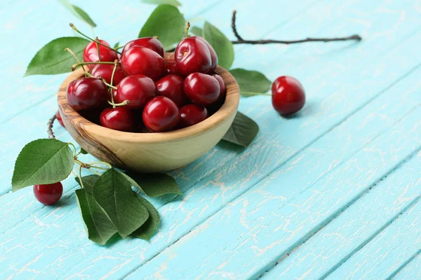 Ripe cherries in a wooden bowl on the background of painted boar — Stock Photo, Image