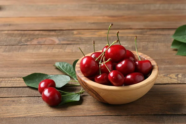 Cerezas maduras en un tazón de madera sobre una mesa de madera — Foto de Stock