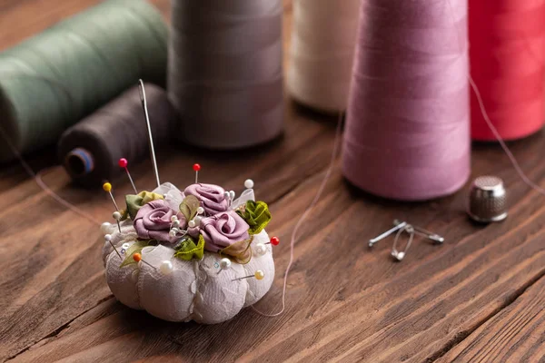 Needle bed with pins, thimble and spools of thread on the backgr — Stock Photo, Image