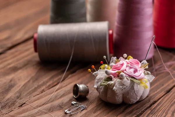 バックグレッグの糸のピン、ティンブルおよびスプールが付いている針のベッド — ストック写真