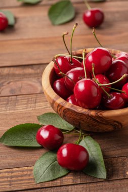 Arkadaki ahşap kasede olgun kirazlar.