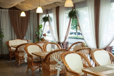 Kafenin iç tarafındaki terasta hasır mobilyalar.