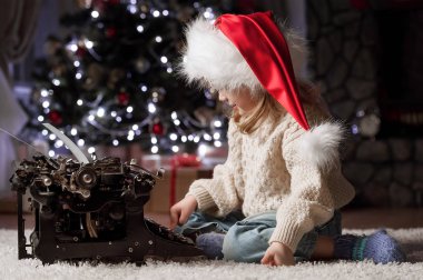 Küçük kız Noel ağacının altında şöminenin yanında oturan Noel Baba'ya bir mektup yazar 