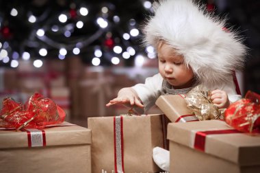 Child goes through the gifts under the Christmas tree clipart