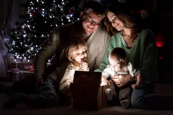 子供を持つ親である魔法の贈り物は クリスマス イヴにクリスマス ツリーの下暖炉のそばで — ストック写真