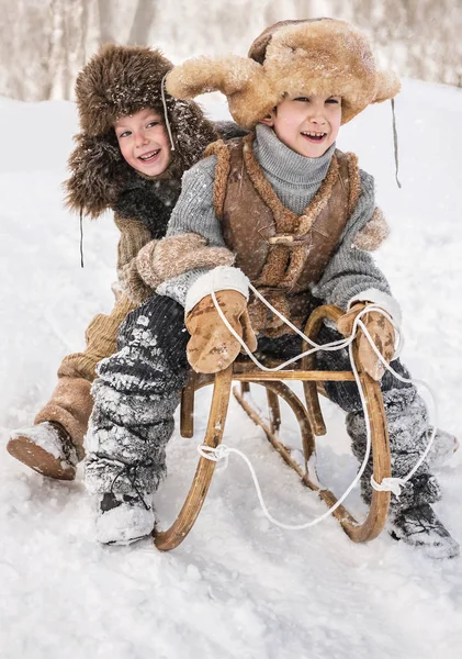 两个男孩雪橇与山温暖的冬天天 — 图库照片