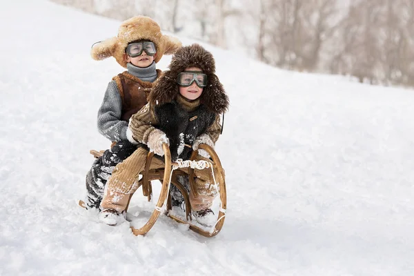 两个男孩雪橇与山温暖的冬天天 — 图库照片