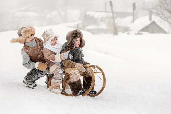 冬季阳光明媚的日子里 三小孩在雪橇上滑下山 — 图库照片