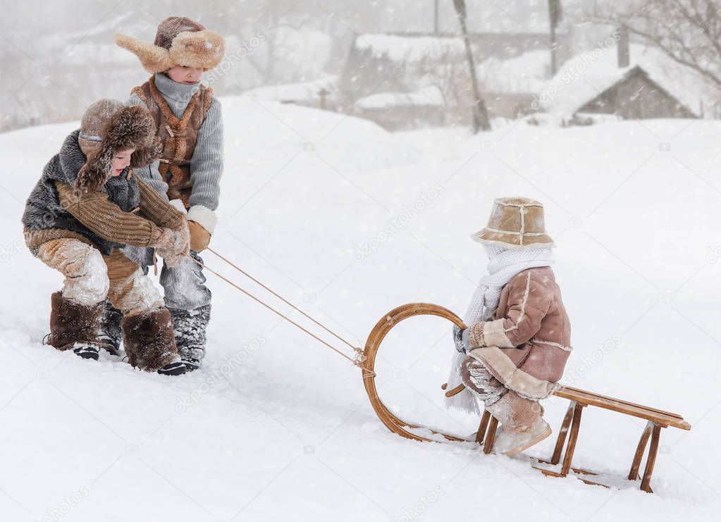 Three children sledding with mountain warm winter day