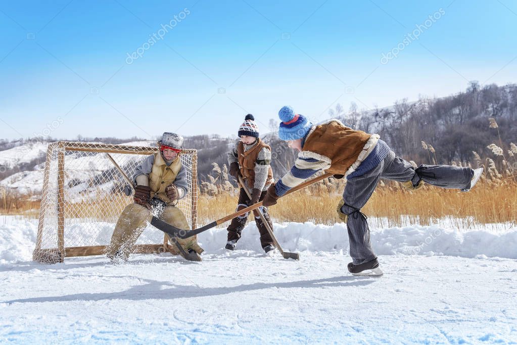Boys play hockey on a frozen lake on a winter sunny day