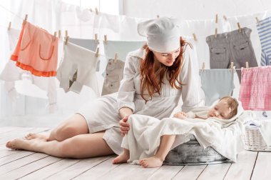 Çamaşırların içinde bebek giysileri ile bir havzasında uyku ile anne