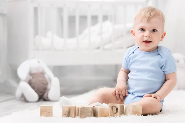 Smiling baby with toys on the carpet in my room