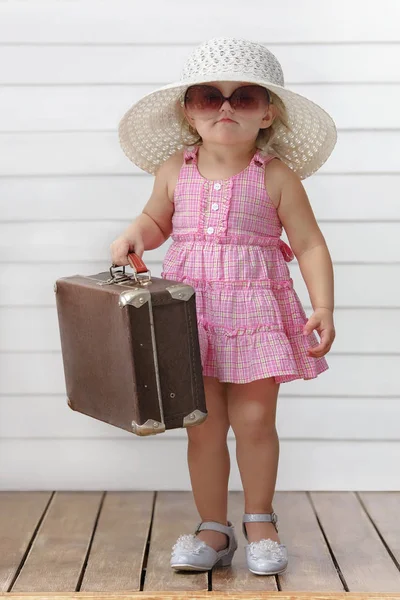 小さな女の子はスーツケースと遊ぶし 旅行に行く夢 — ストック写真