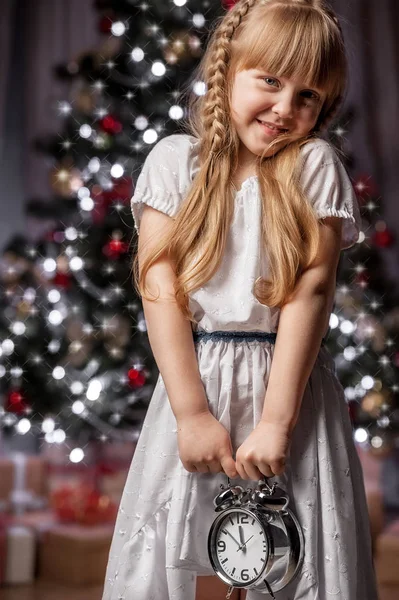 Portrait of girl with alarm clock under the Christmas tree — Stock Photo, Image