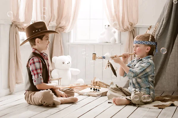 Meninos como índio e cowboy brincando em seu quarto — Fotografia de Stock