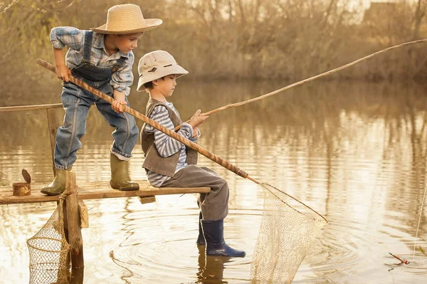 男孩们在湖上的桥上钓鱼 — 图库照片