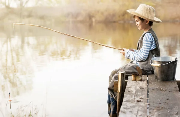 Garçon pêche sur un pont sur le lac — Photo