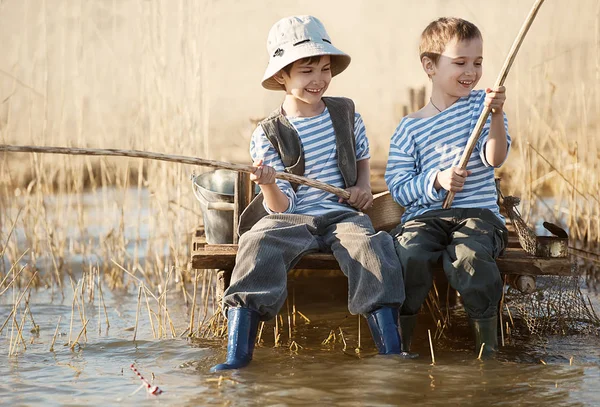 Pojkar fiskar på en bro på sjön — Stockfoto
