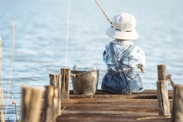 Boy fishes on a bridge on the lake — Stock Photo, Image