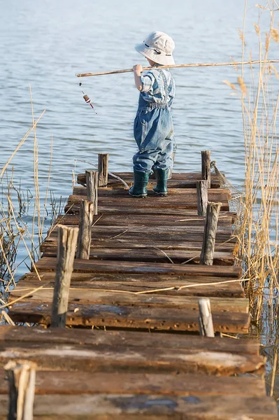 Ragazzo pesci su un ponte sul lago — Foto Stock