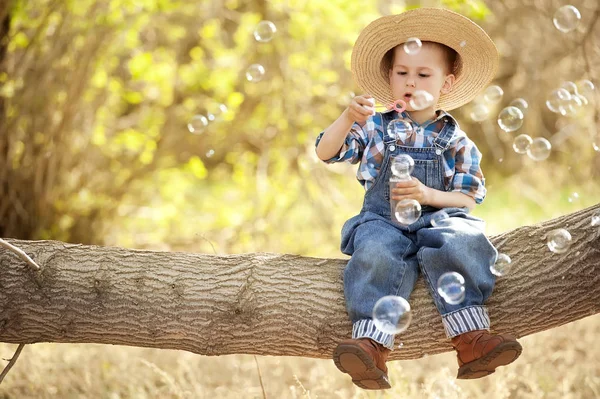 Kind met zeepbellen op een boomtak — Stockfoto