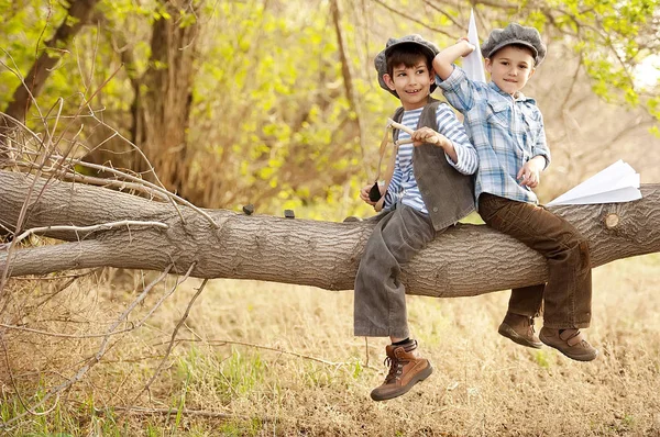 Boys let paper airplanes and shoot with the slingshot, sitting on a tree branch — Stock Photo, Image