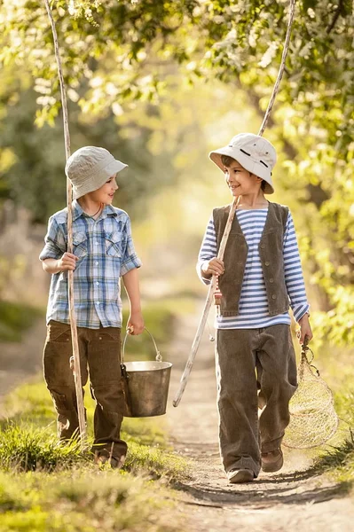 Jongens gaan vissen met hengels op een landelijke straat — Stockfoto