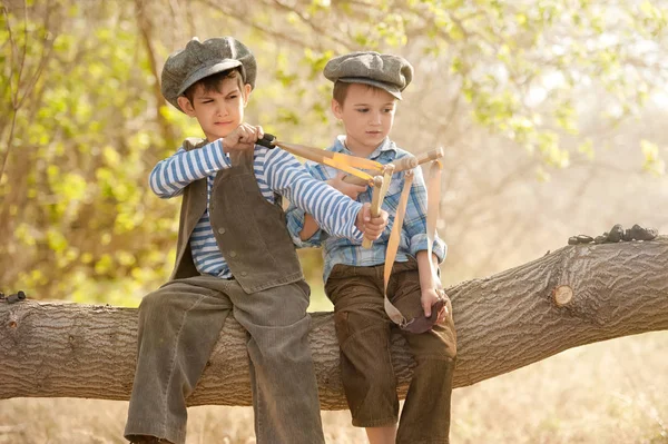 Rapazes com fisgas sentados num galho de árvore — Fotografia de Stock