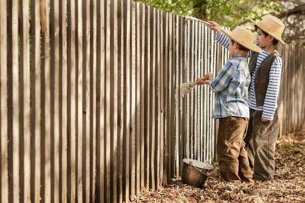 男の子は古いフェンスを塗ります — ストック写真