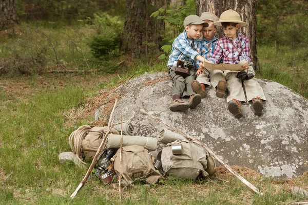 Rapazes viajantes sentados em uma grande rocha com um mapa — Fotografia de Stock