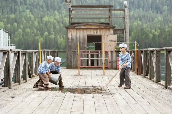 Drie jongens zeilers op de pier van een bergmeer — Stockfoto