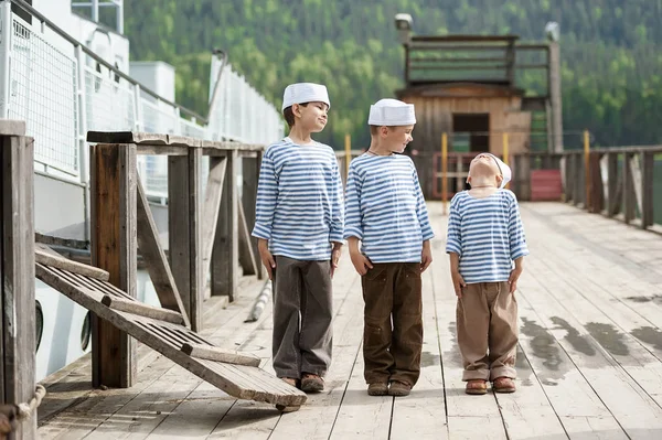 Tre ragazzi marinai sul molo di un lago di montagna — Foto Stock